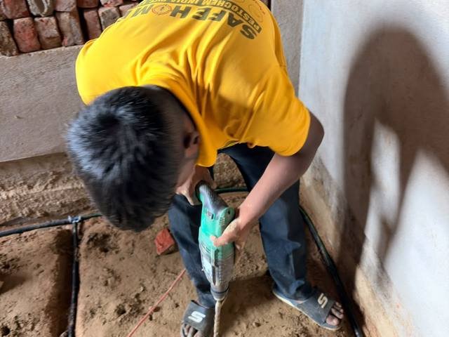 Technician positioning termite reticulation pipework before backfilling